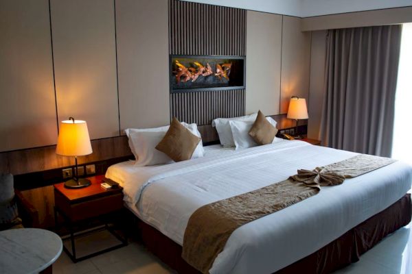 A cozy, modern hotel room with a large bed, two bedside tables with lamps, neutral tones, and a decorative wall feature above the bed.
