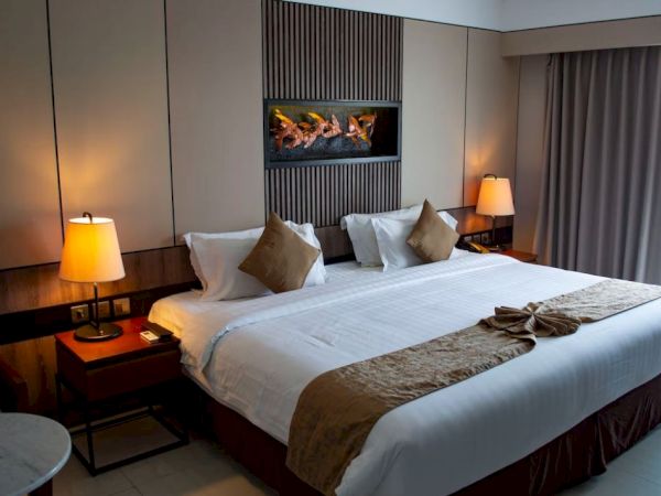 A cozy, modern hotel room with a large bed, two bedside tables with lamps, neutral tones, and a decorative wall feature above the bed.