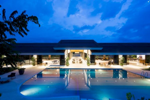 A luxurious resort or hotel with a large swimming pool, illuminated at night with modern architecture and an inviting ambiance.