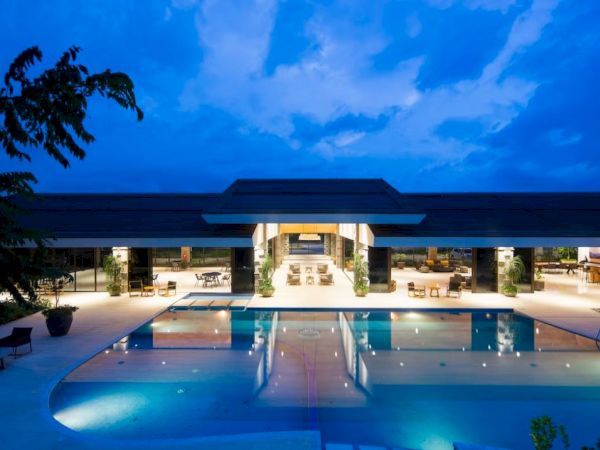 A luxurious resort or hotel with a large swimming pool, illuminated at night with modern architecture and an inviting ambiance.