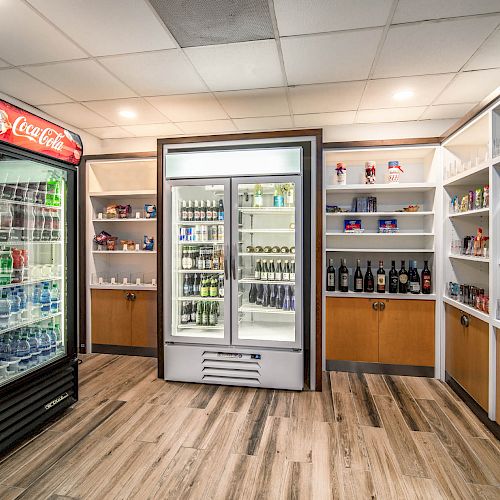 The image shows a well-lit convenience store interior with fully stocked shelves, beverages in coolers, and various snacks and items on display.