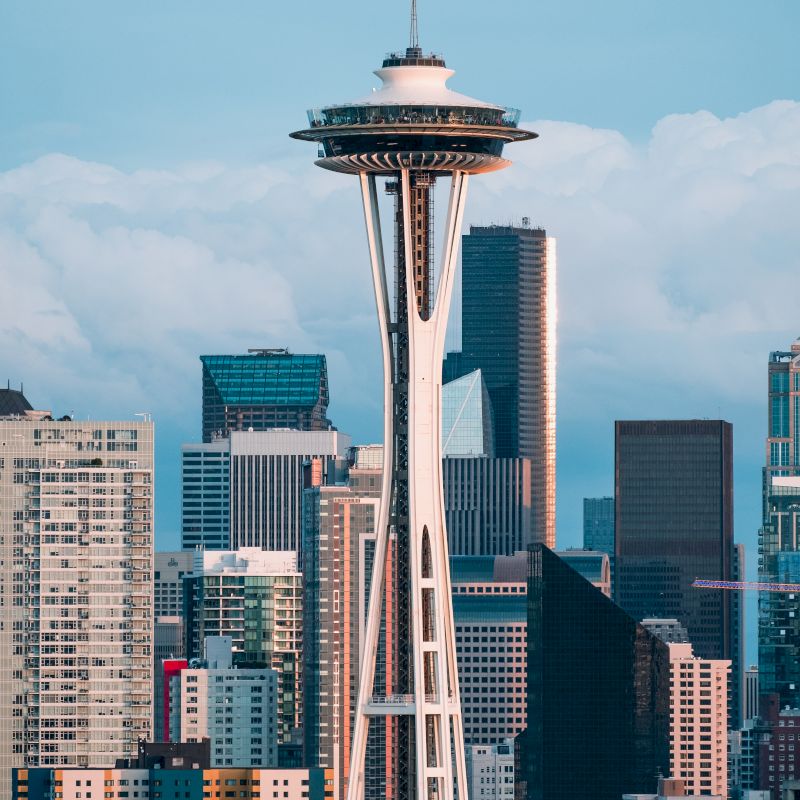 The image features a city skyline with the prominent Space Needle, an iconic observation tower located in Seattle, Washington, surrounded by buildings.